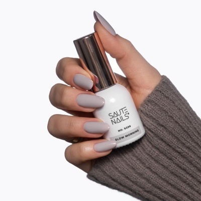 Mão com unhas pintadas segurando frasco de verniz SAUTE NAILS