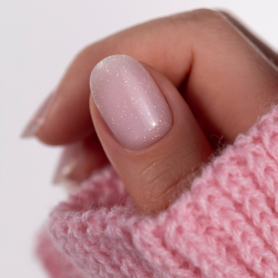Unhas com verniz rosa claro e brilhos com manga de camisola rosa