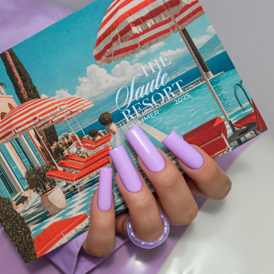 Mão com unhas lilás segurando caixa com ilustração de resort e texto THE Haute RESORT SUMMER 2025