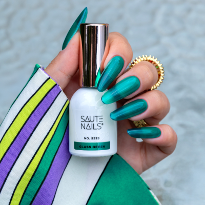 Unhas longas verdes segurando frasco de verniz SAUTE NAILS