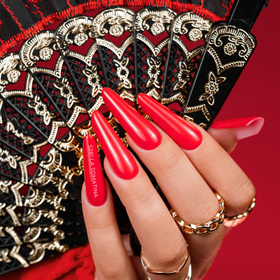 Mão feminina com unhas vermelhas segurando leque preto e dourado