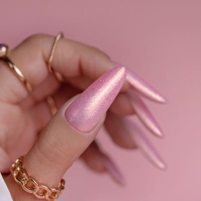 Unhas compridas rosa brilhante com anéis dourados e fundo rosa