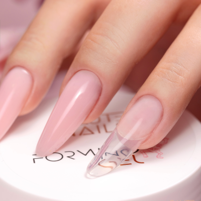 Unhas compridas cor rosa com gel transparente e recipiente branco com texto