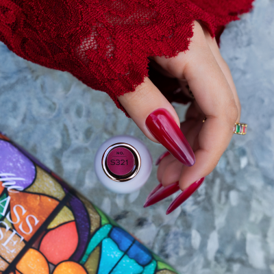 Mão com unhas vermelhas segurando esmalte SAUTE NAILS cor S321 sobre vidro texturizado