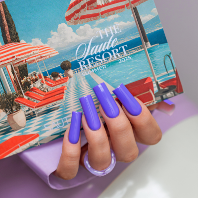 Mão com unhas roxas segurando embalagem com piscina e chapéus de sol vermelhos e brancos