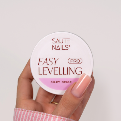 Embalagem redonda branca do produto SAUTE NAILS EASY LEVELLING PRO SILKY BEIGE com mão segurando e unhas bege.