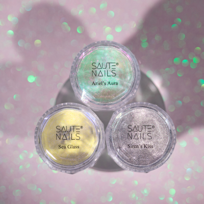 Três potes de glitter para unhas SAUTE NAILS sobre fundo rosa brilhante