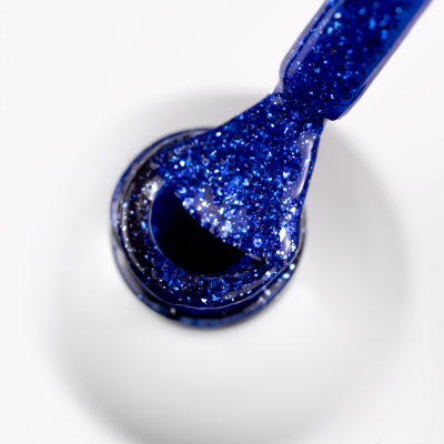 Frasco aberto de verniz para unhas azul com glitter e pincel embebido