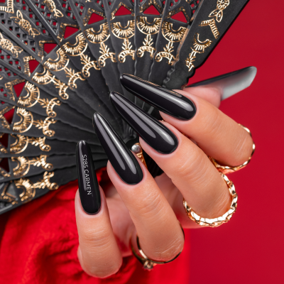 Mão com unhas pretas brilhantes segurando leque decorativo preto e dourado