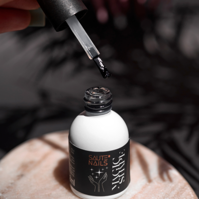 Frasco branco de verniz de unhas com rótulo identificado e aplicador com verniz preto