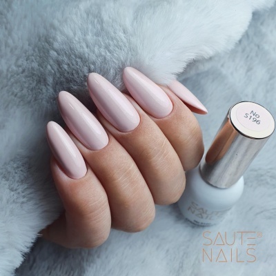 Unhas rosa nude com verniz de gel e garrafa de verniz branco com tampa prateada.