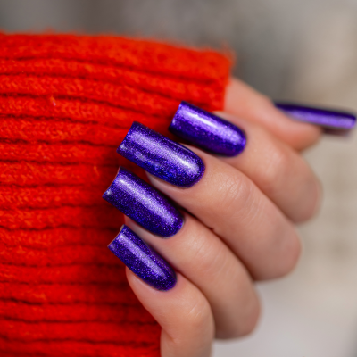 Unhas compridas com verniz roxo metálico brilhante e manga de camisola vermelha