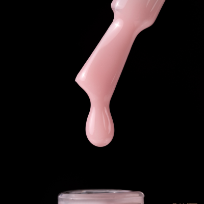 Frasco aberto de verniz de unhas rosa com gota pendurada no pincel