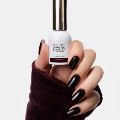 Frasco branco de verniz de unhas SAUTE NAILS Dark Roast com mão segurando