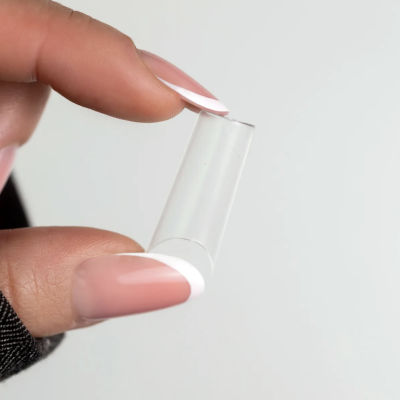 Dedos com unhas francesinhas a segurar tubo transparente