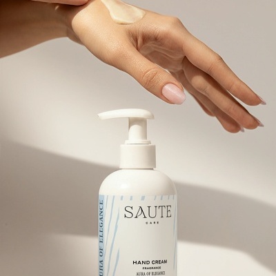 Frasco de creme de mãos SAUTE CARE com doseador e mão aplicando creme