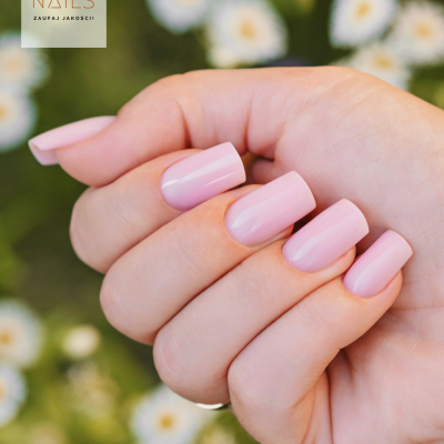 Mão com unhas rosa claro e fundo de flores brancas desfocadas