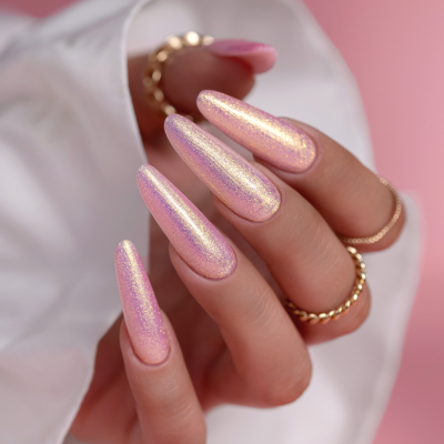 Unhas compridas rosa iridescente com anéis dourados em fundo rosa