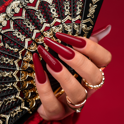 Unhas vermelhas longas segurando leque dourado e preto