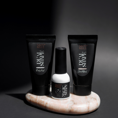 Produtos para unhas SAUTE NAILS em embalagem preta e branca sobre base de pedra oval