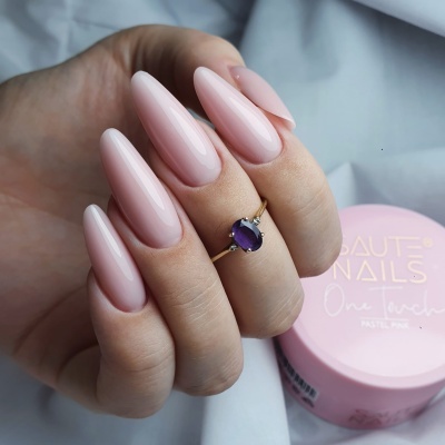 Mão com unhas longas rosa pastel e anel dourado com pedra roxa