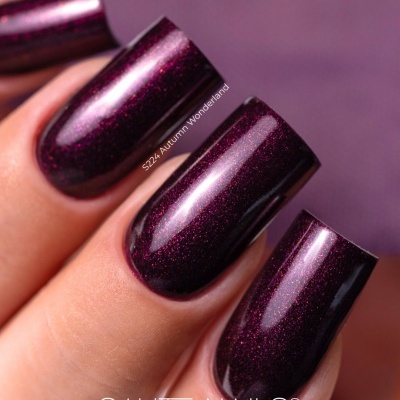Unhas com verniz roxo escuro cintilante com texto e marca visíveis