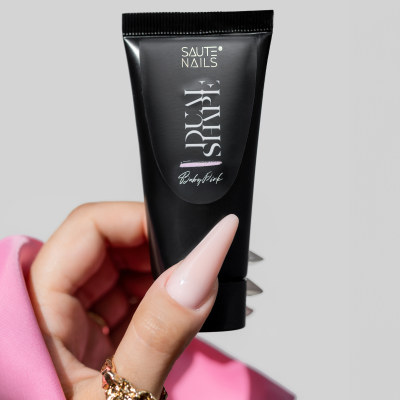 Mão com unhas rosa claro segurando tubo preto de SAUTE NAILS Dust Shape