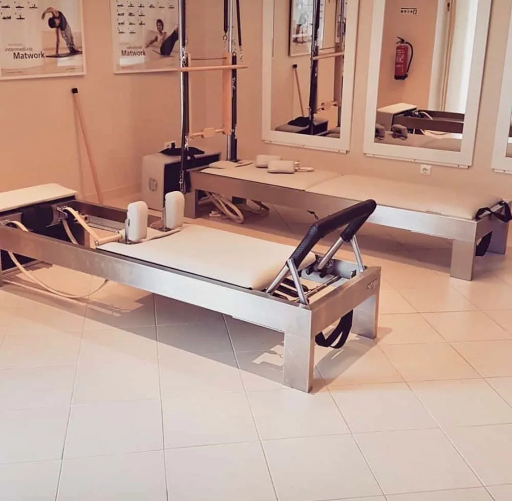 Equipamentos de Pilates Reformer em sala com espelhos e quadros