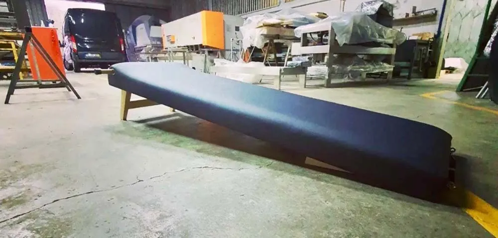 Banco comprido almofadado azul escuro com pernas de madeira em armazém