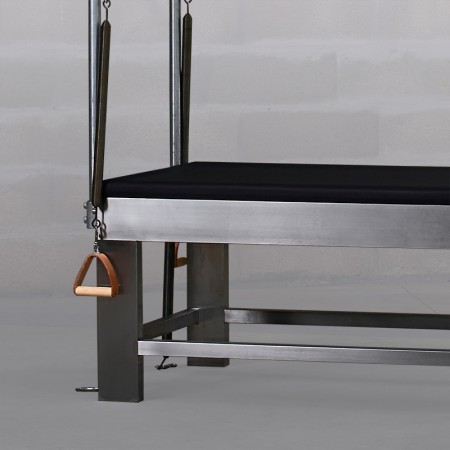 Cama de Pilates com estrutura metálica e almofada preta, com alças de madeira penduradas