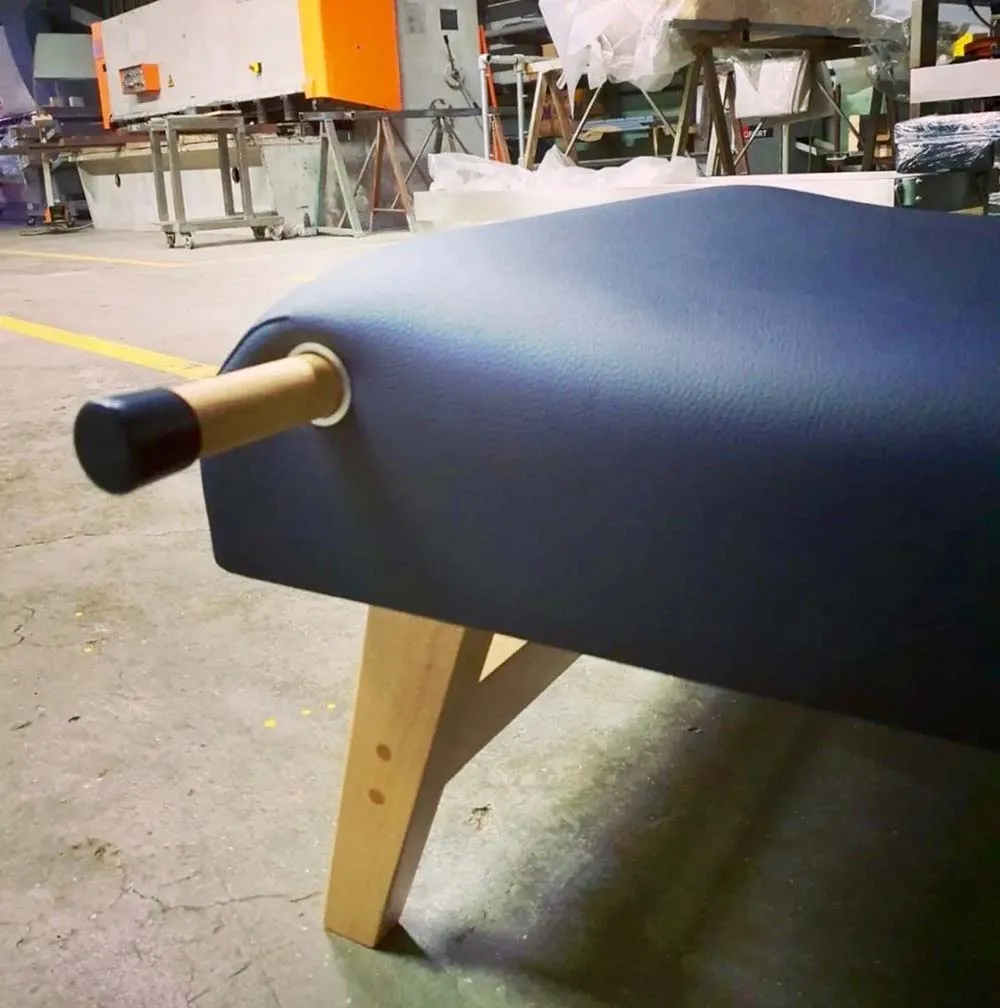 Banco azul escuro com pernas de madeira clara e apoio cilíndrico