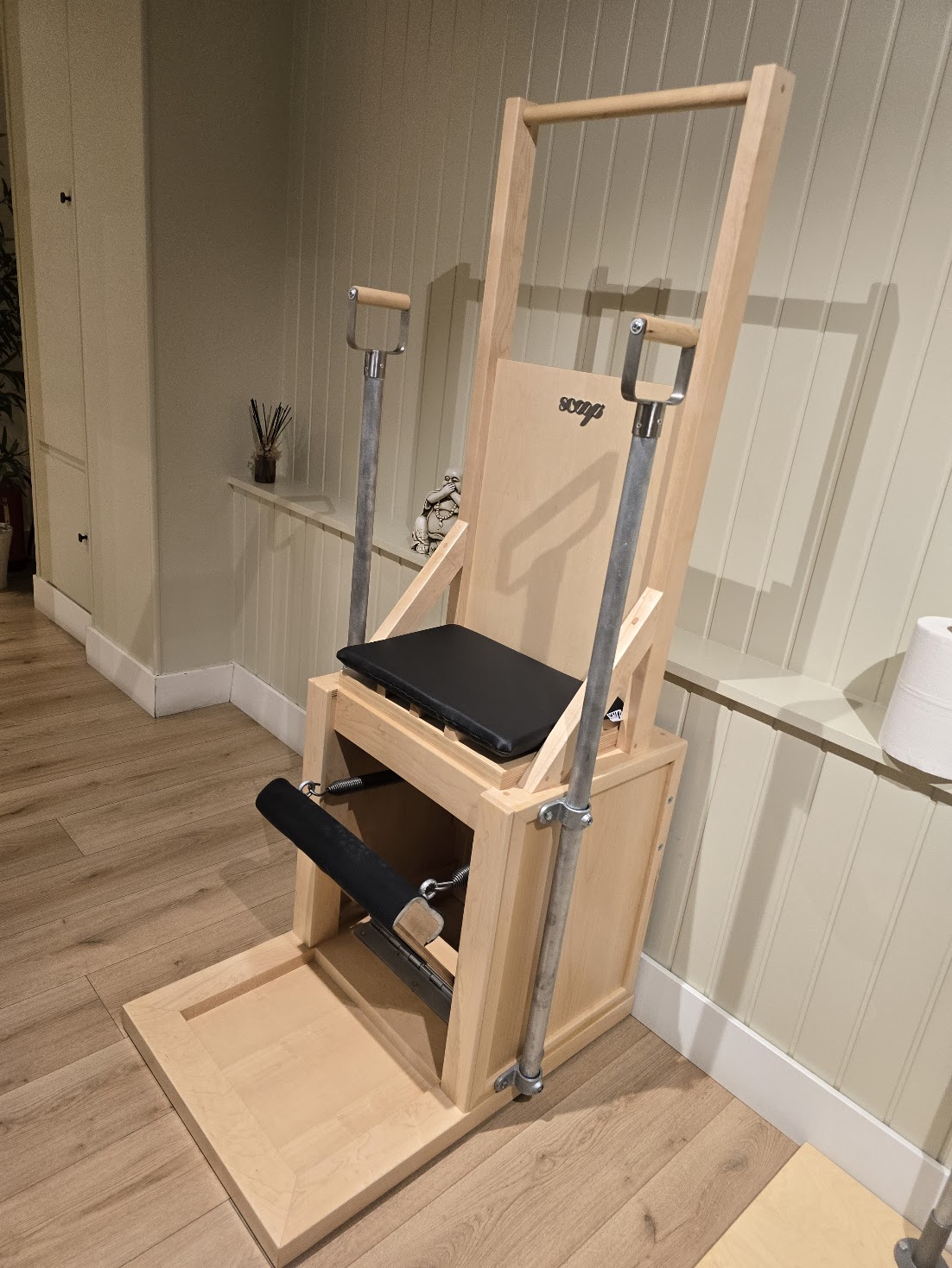 Cadeira de exercício em madeira com barras metálicas e assento preto