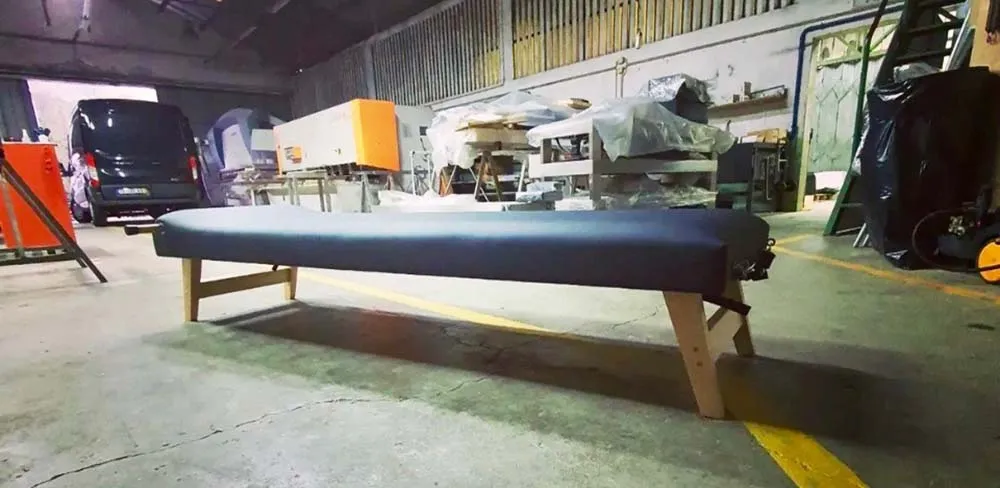 Banco estofado azul com estrutura de madeira em espaço industrial.