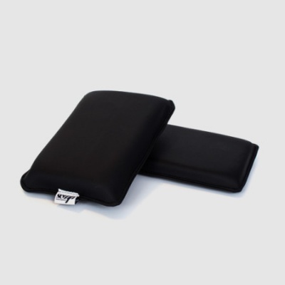 Duas almofadas retangulares pretas com etiqueta branca com texto VZ, em fundo cinzento claro