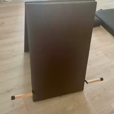 Colchão dobrável castanho com estrutura de madeira clara no chão de madeira clara