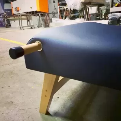 Banco azul escuro com pernas de madeira clara e apoio cilíndrico