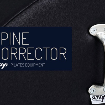 Equipamento 'Spine Corrector' de pilates com pega metálica e base preta