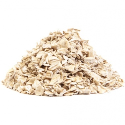 Pilhas de flocos de aveia bege claro sobre fundo branco.