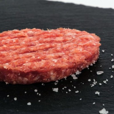 Hambúrguer cru de carne moída com sal grosso em placa preta