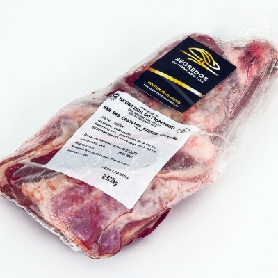 Peça de carne embalada a vácuo com rótulos preto, amarelo e branco numa superfície branca