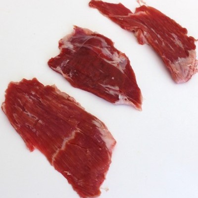 Três fatias de carne crua vermelha com gordura branca em fundo branco