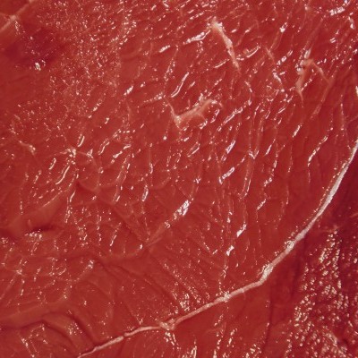 Pedaço grande de carne crua vermelha sobre superfície de madeira