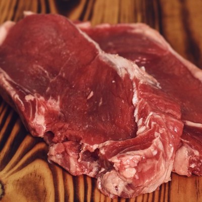 Duas peças de carne crua vermelha sobre tábua de madeira