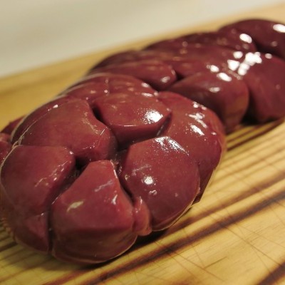 Rim cru vermelho-escuro sobre tábua de madeira clara.