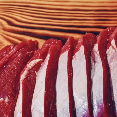 Fatias de carne vermelha sobre tábua de madeira