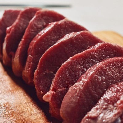 Fatias de carne vermelha crua numa tábua de madeira