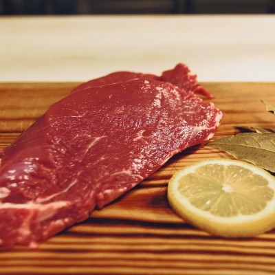 Bife cru com limão e folhas de louro numa tábua de madeira