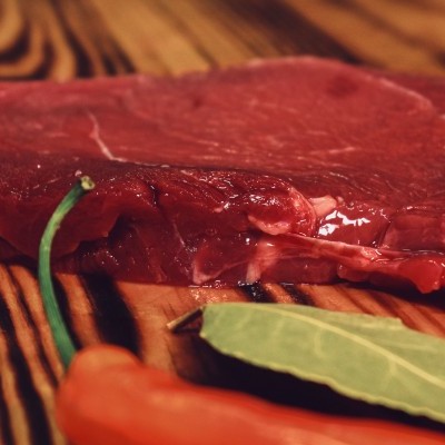Bife cru de carne vermelha com folha de louro e pimenta sobre tábua de madeira