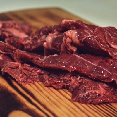 Pedaços de carne vermelha crua sobre tábua de madeira listrada