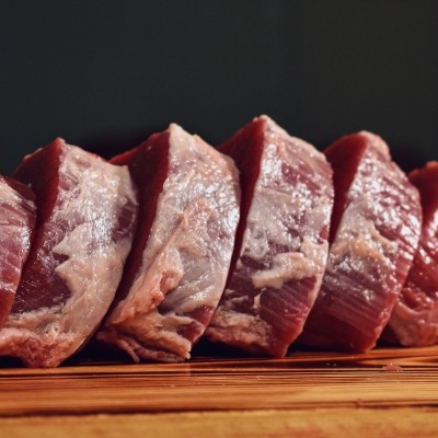 Pedaços de carne fresca cortada dispostos em linha numa madeira clara
